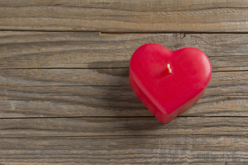 Red heart shaped candle on a wooden surface