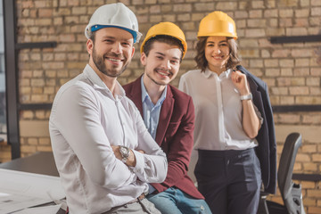 team of happy architects in hard hats looking at camera