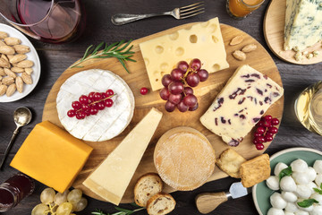 Various types of cheese with wine on rustic background