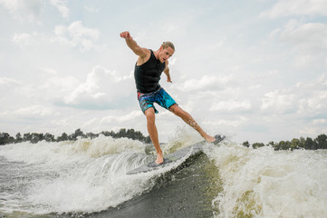 Athletic man wakesurfing on the board against the sky