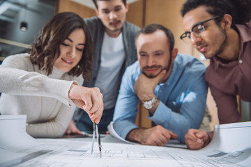 close-up shot of group of architects drawing building plan together at office