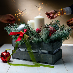 Concept of celebration Merry Christmas and Happy New Year! Composition with gray box with fir tree branches, candles and Christmas toys on light background