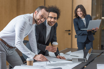 team of happy architects working with building plans at conference hall of office