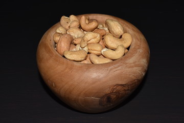 Cashew nut grain in a wooden mortar on the black table, black background
