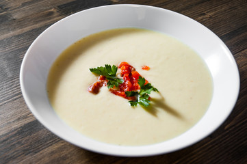 Creamy fish soup with salmon, potatoes, onions, cauliflower and carrots on a wooden background