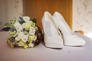wedding bouquet with shoes on the bad near  the door
