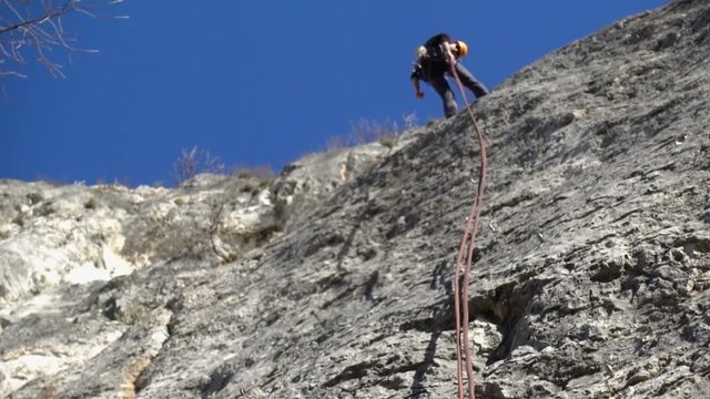 Unfocused footage of a rock climber cliff rappelling