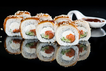 Appetizing fresh set of sushi rolls with rice, cream cheese, salmon, cucumber, conger and sesame on dark background