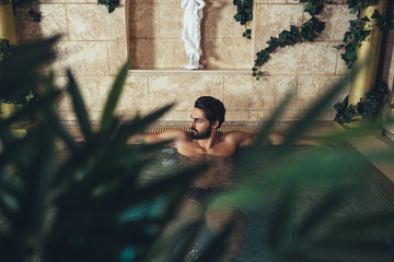 Young handsome bearded man enjoying and relaxing in spa center. 