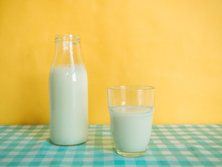 Pouring milk into glass on yellow background