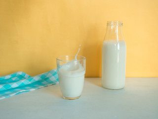 Pouring milk into glass on yellow background
