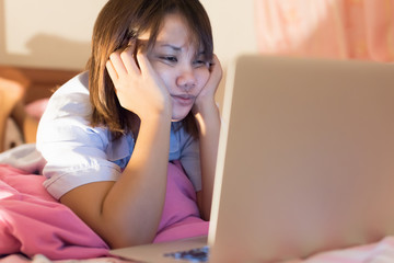 Fototapeta premium Asian young woman using laptop on her bed before sleep in selective focus..
