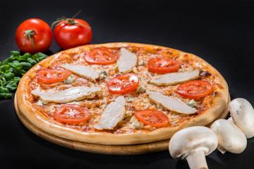 Chicken-blue pizza with tomato, mozzarella and Dor Blue cheeses on wooden board on dark background
