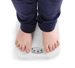 Overweight boy standing on floor scales against white background