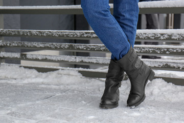 Stylish woman wearing warm shoes on city street in winter