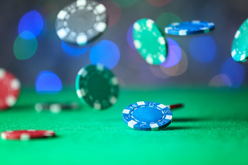 Gambling chips falling on green table in casino