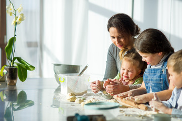 Mother teaches her three children to cook.