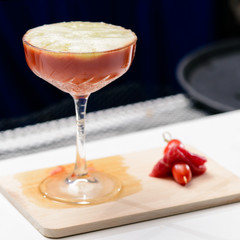 Martini glass with red alcoholic cocktail on the wooden board