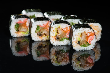 Traditional Japanese cuisine. Tasty sushi rolls with rice, cream cheese, salmon, cucumber and tuna on dark background