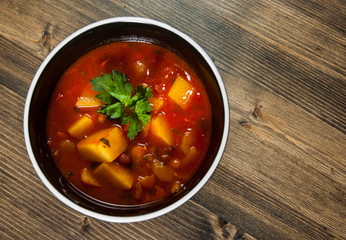 Bean and vegetables soup in ceramic bowl on wooden table