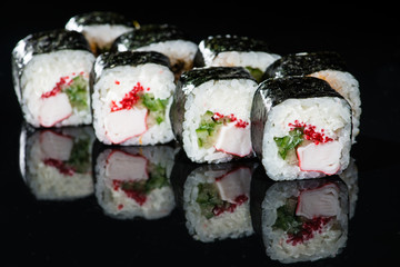 Traditional Japanese cuisine. Tasty sushi rolls with rice, cream cheese, cucumber and tuna on dark background