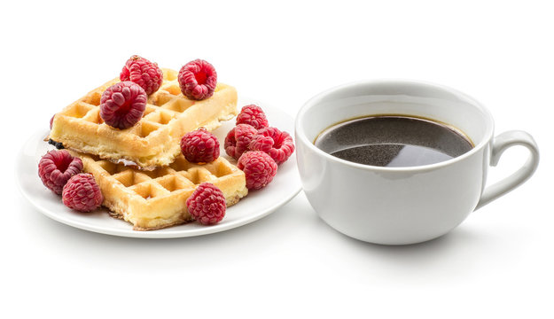 Traditional waffle (Belgian) with honey and fresh raspberries on a saucer with a cup of coffee without milk isolated on white background sweet delicate and airy delicious breakfast.