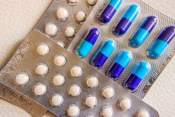 Blisters pack of blue-purple capsules and white tablets on white background