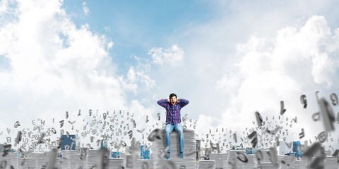 Attractive man sitting on pile of paper documents.