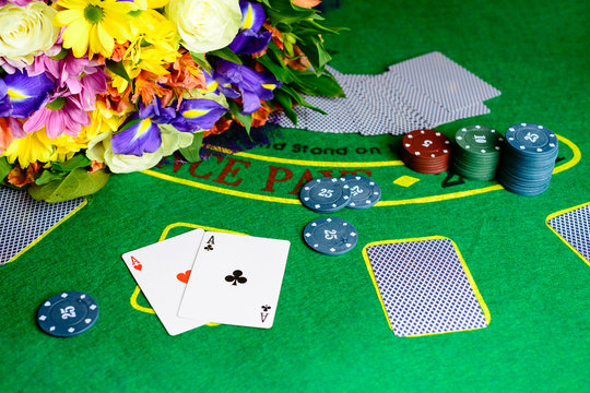 Concept of casino, playing cards and money. Stacks of poker chips, aces and bouquet of flowers on green table at the casino