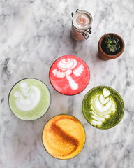 Four different colored latte coffee, style of foam art, natural organic beverages in modern cafe on...