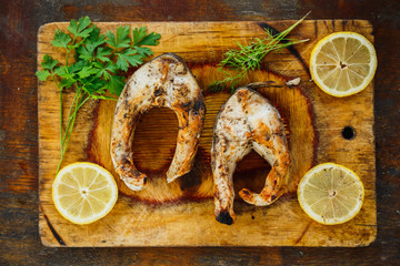 yammy grilled fish pieces with parsley and lemon slices on the board