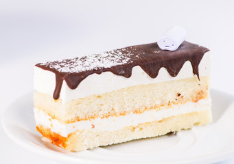 Slice of delicious sweet layered glaze cake on light background