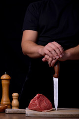 Hands man with knife and raw beef