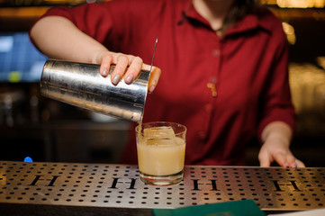 Fototapeta na wymiar Female bartender pouring a fresh cocktail into the glass