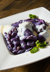 Dumplings with blueberries and cream. on a wooden background