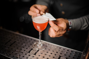Barman decorating a cocktail glass with a paper flying airplane