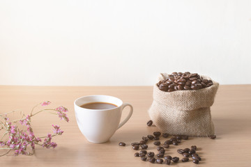 Coffee cup with coffee beans placed on a wooden table.