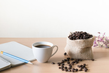 Coffee cup with coffee beans placed on a wooden table.