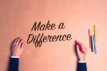 Hand writing a phrase Make a Difference on paper