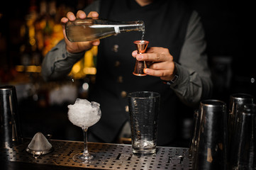 Fototapeta na wymiar Barman making a fresh alcoholic cocktail pouring a drink