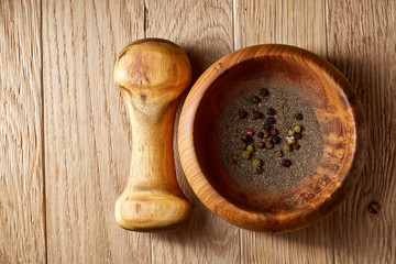Top view close-up picture of wooden pestle and mortar with spicies on rustic wooden background, shallow depth of field