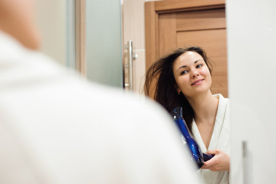 Portrait of prety young woman using hairdryer