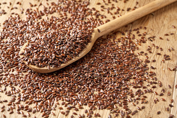 Wooden spoon with flax seeds on rustic background, top view, close-up, shallow depth of field, selective focus