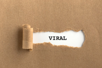 The text VIRAL behind torn brown paper