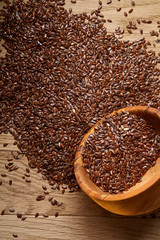 An overturned wooden bowl with linseeds on a rustic background, close-up, shallow depth of field, selective focus