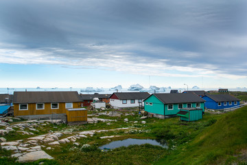 Iceberg and village. Greenland`s life