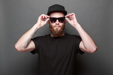 Hipster handsome male model with beard wearing black blank t-shirt with space for your logo or...
