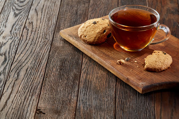 Cup of tea with cookies on a wooden cutting board on vintage background, top view