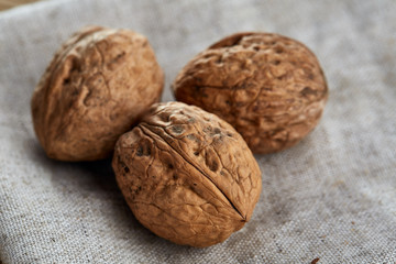A stack of hard shells of walnuts piled together on light grey fabric cotton tablecloth, selective focus