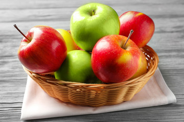 Juicy apples in wicker basket on wooden table